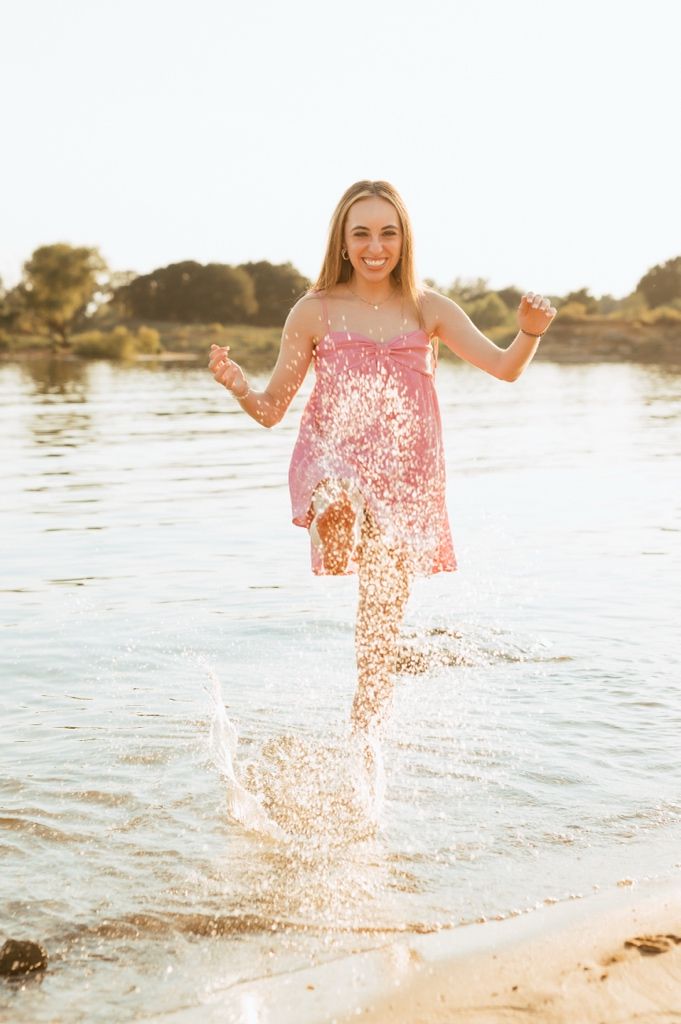 Splashing through shallow water at sunset creating a spray of sparkling droplets at the beach.