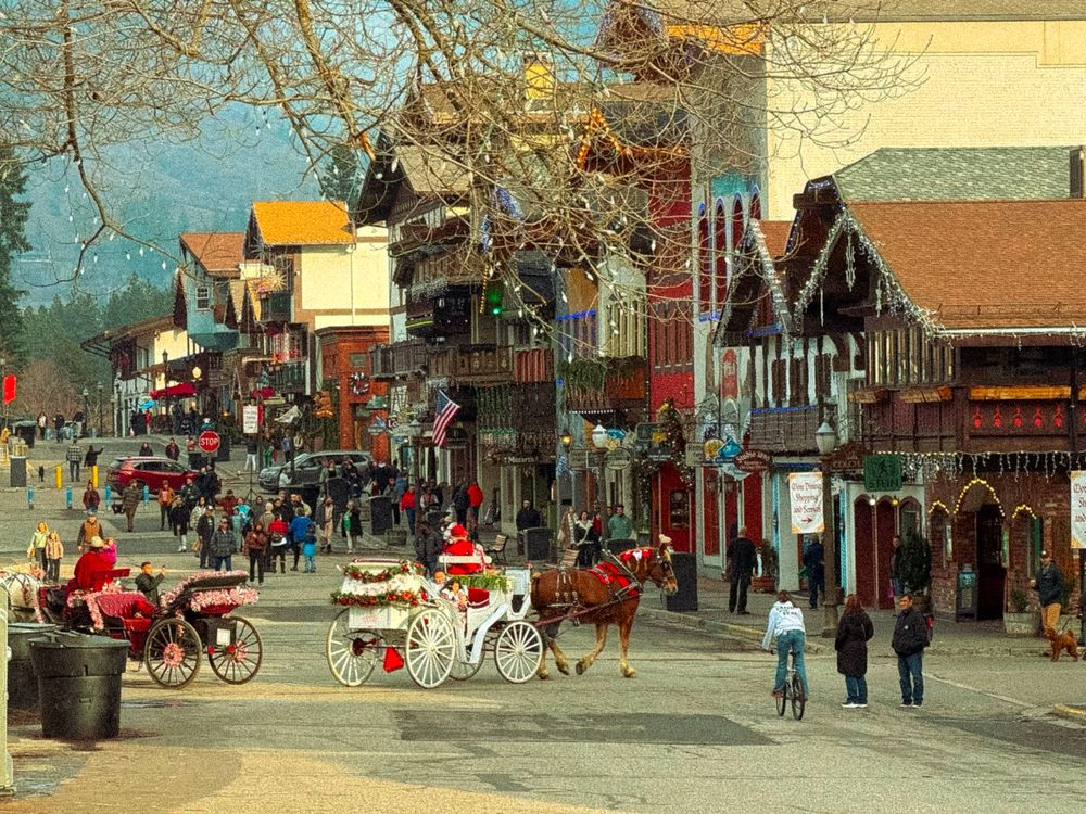 Charming Christmas village street with horse-drawn carriage, festive decorations, and holiday shoppers in a quaint town.