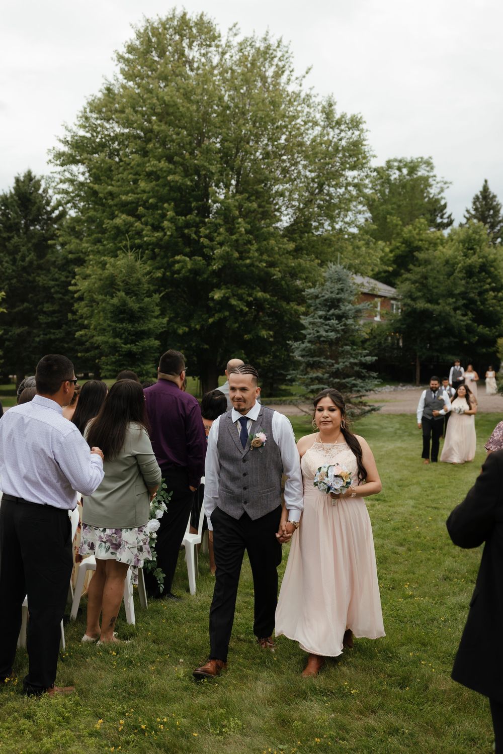 Wedding guests gather on a grassy lawn during an outdoor summer celebration.
