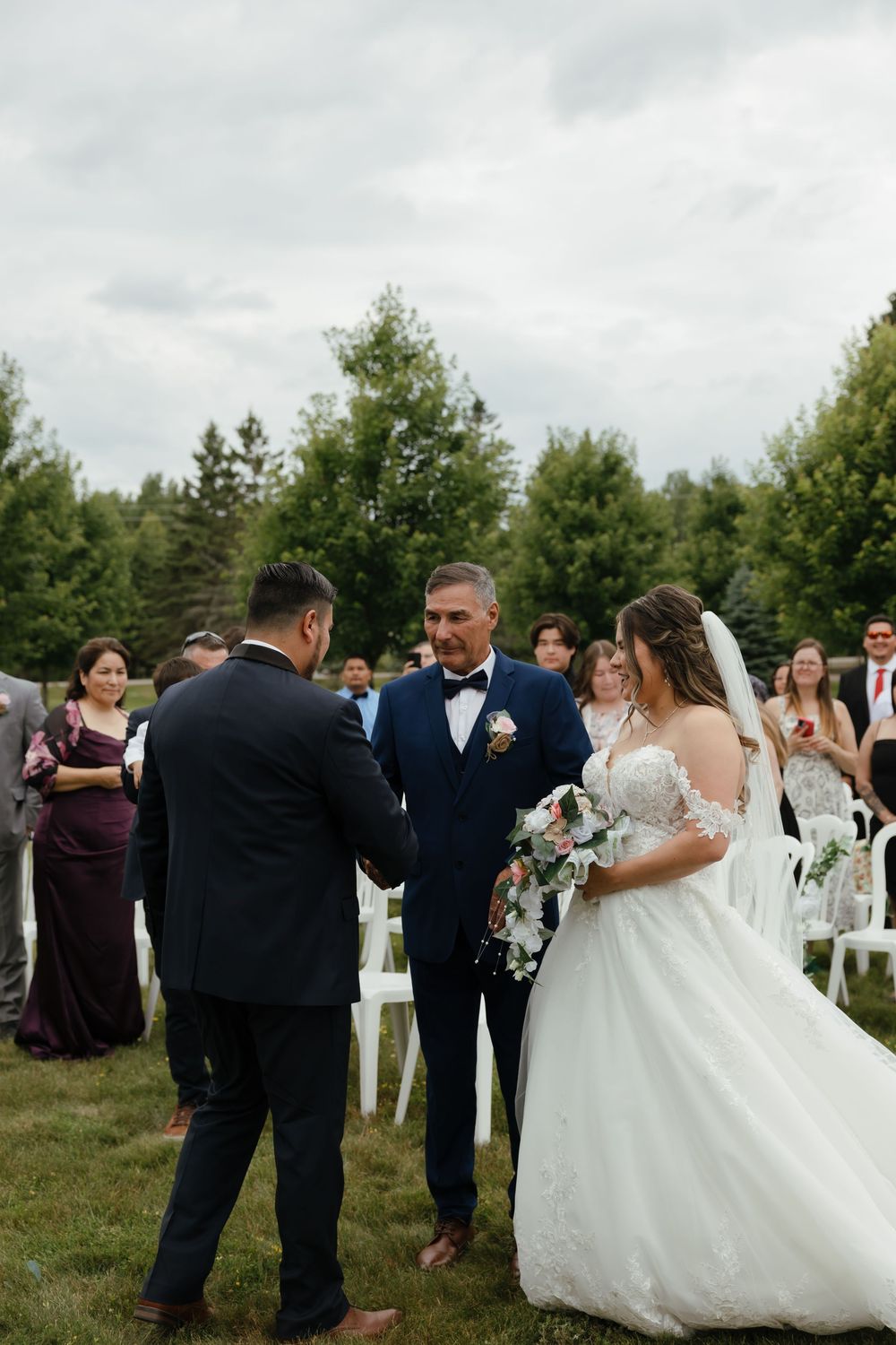 Wedding guests gather outdoors to celebrate as newlyweds dance together during outdoor garden reception.