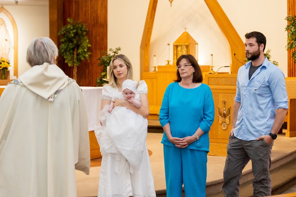 Wedding guests in formal attire gather in warmly lit church hallway during special occasion celebration.