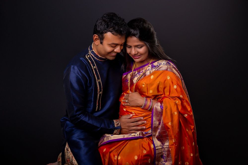 A couple in traditional Indian attire, with navy blue and bright orange outfits, embrace in a romantic photoshoot series.