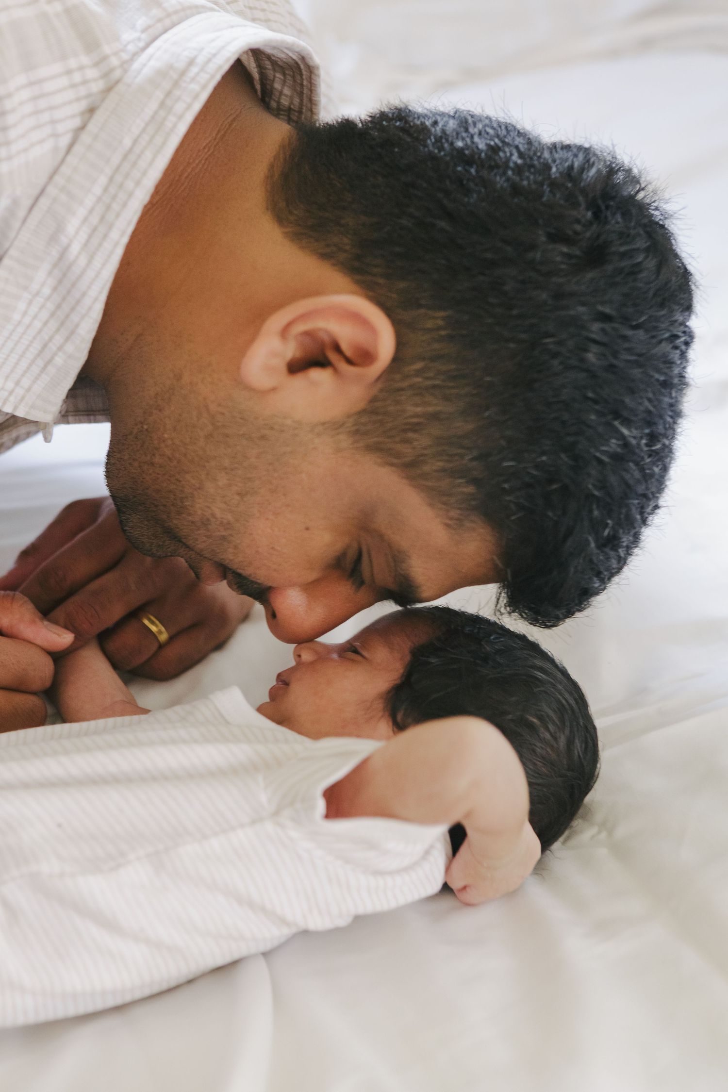 Father cuddles newborn baby during relaxed home photography session in NYC
