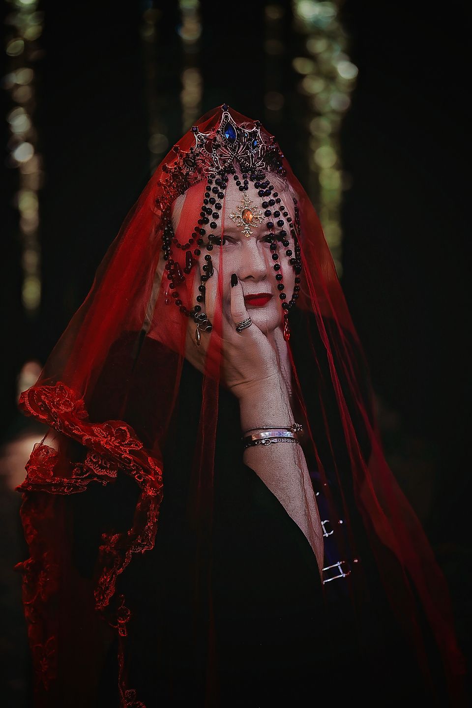 An artistic photo sequence showing someone wearing a dramatic red lace veil in a dark forest setting.