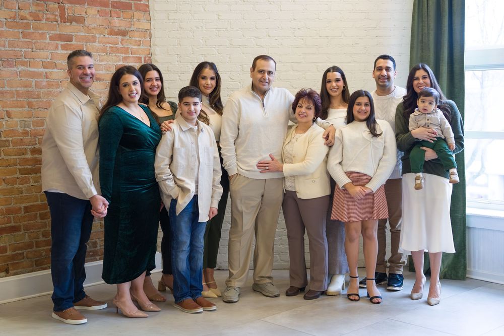 A group of people standing together against a brick wall in coordinated casual outfits for a photo session.