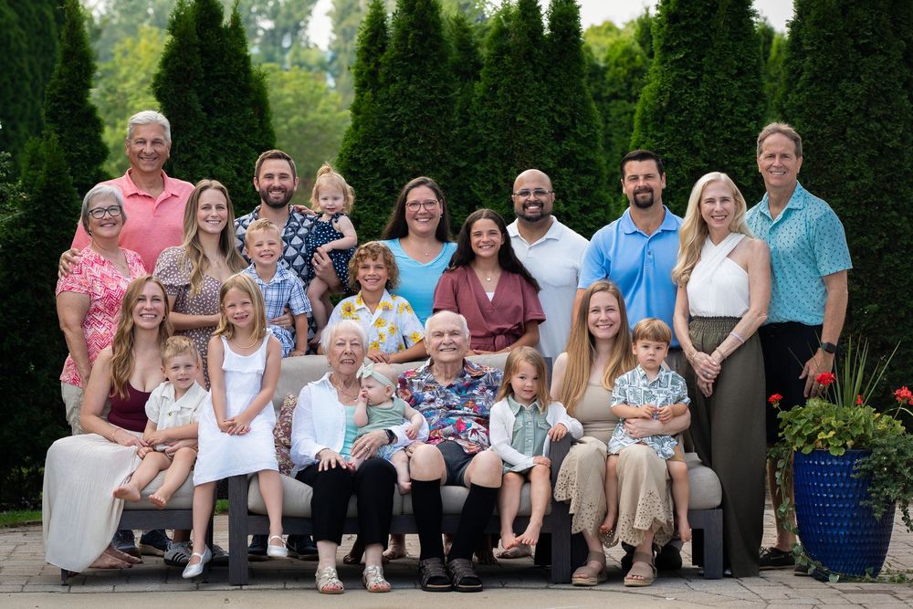 Multiple groups of people sitting outdoors in casual attire during a photo session in a garden setting.