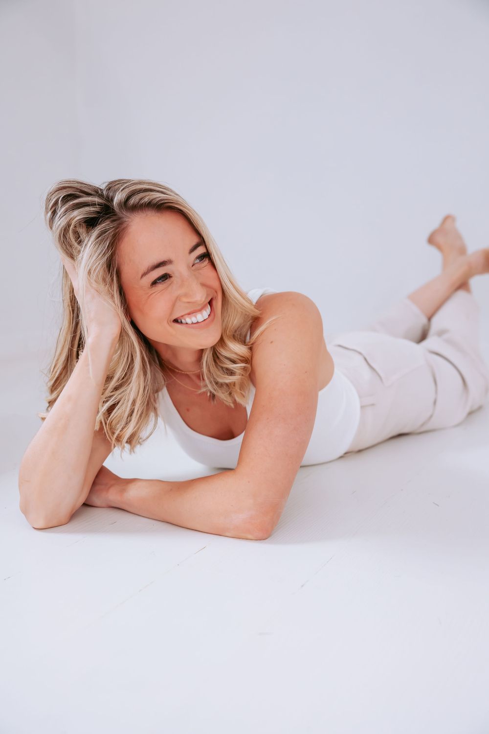 Candid lifestyle photo showing joyful expression while lying on white background.