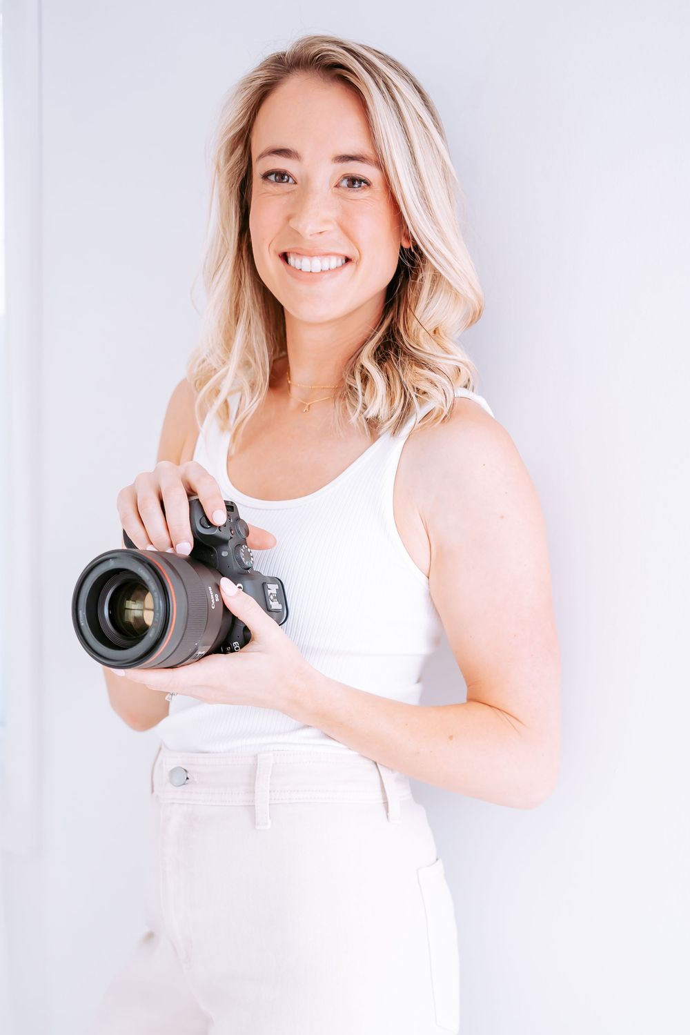Professional photographer showing camera equipment in bright minimalist studio setting.
