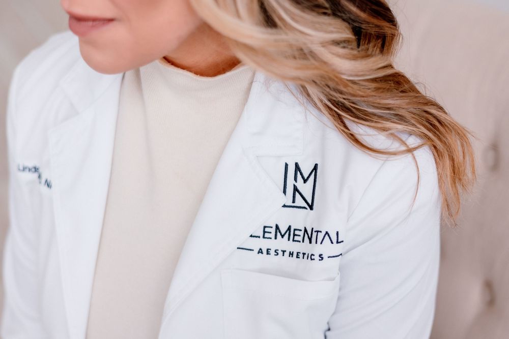 Close-up of white lab coat with Elemental aesthetics logo embroidered on chest.