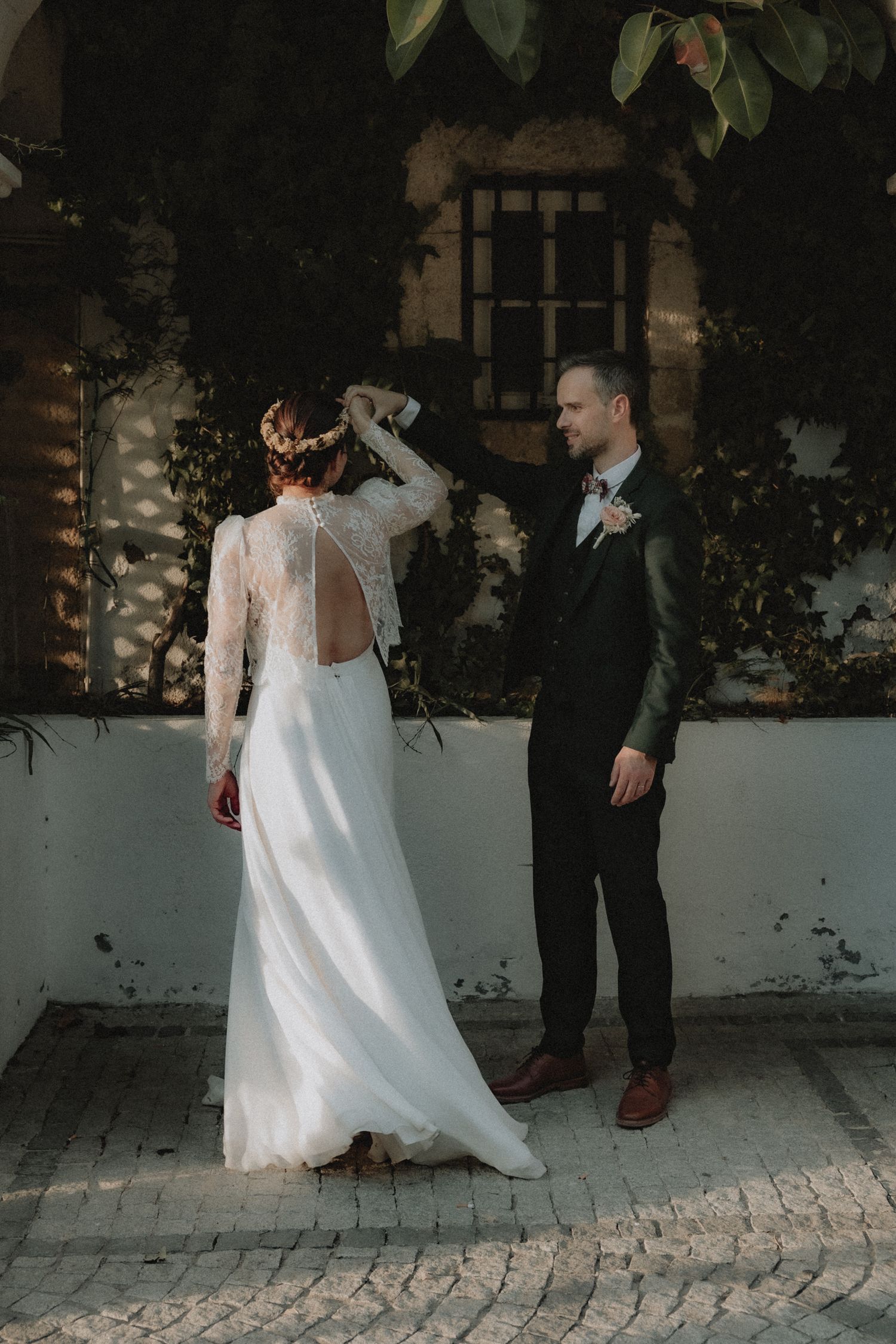 Groom spinning bride in white lace dress in a courtyard in Santorini