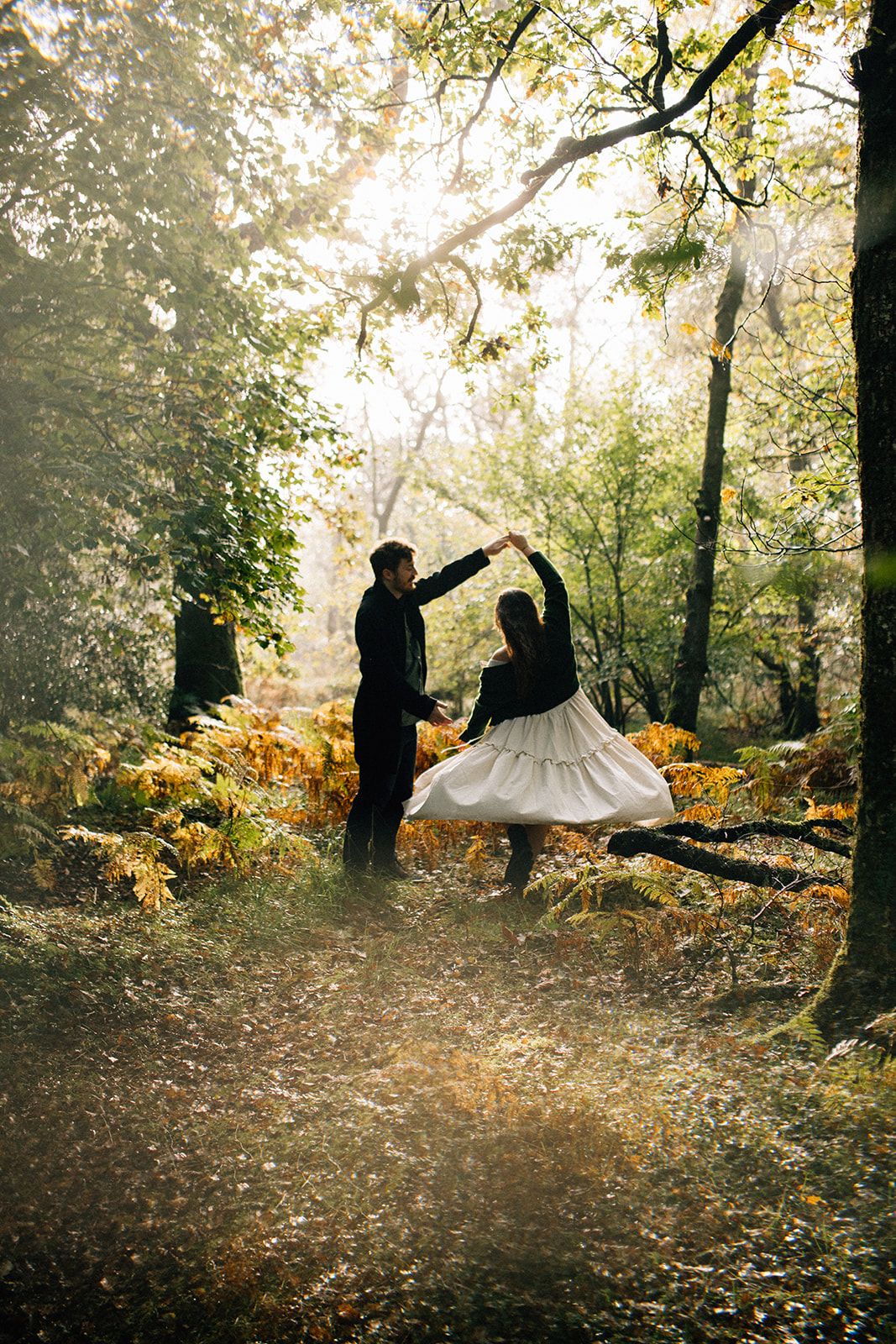Couple shares intimate moment in lush garden with giant leaves in foreground.