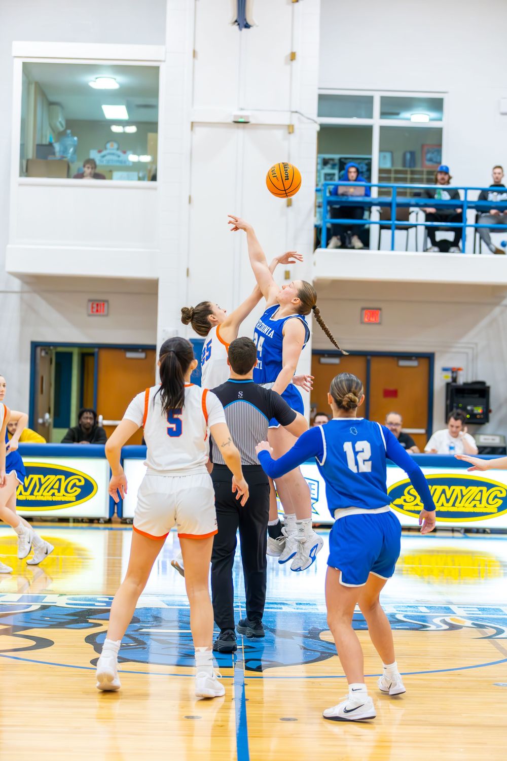 Basketball players compete for possession during an intense game on a blue and white court.