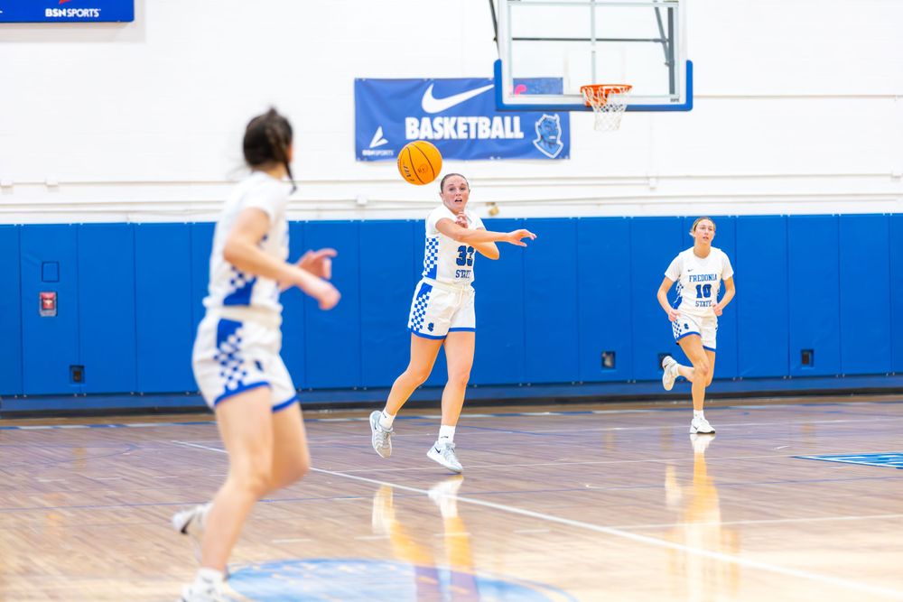 Basketball players sprint down the court during a fast break play in a gymnasium.