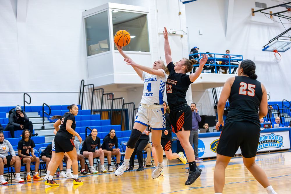 Players battle for position during a basketball game on a bright indoor court.
