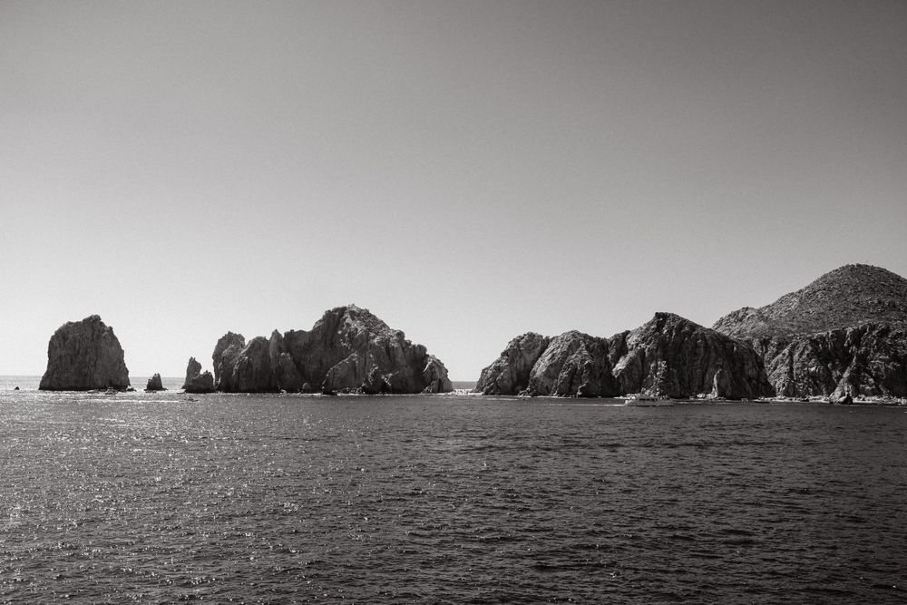 Black and white seascape featuring dramatic rock formations jutting from ocean waters. Archival wall art print for thoughtful interiors.