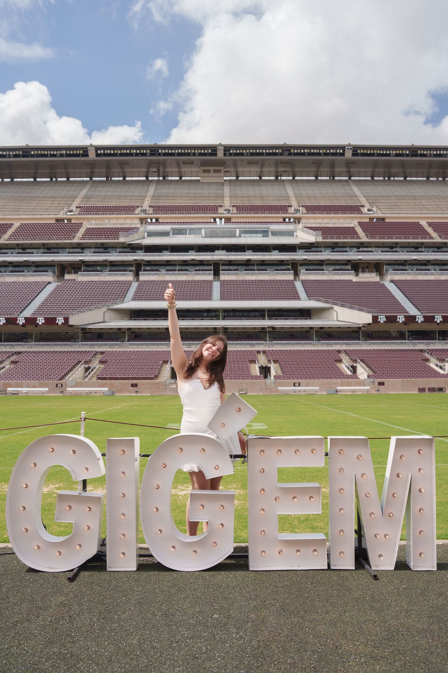 Two people exchange items while a third person in maroon smiles in the background at Texas A&M University.