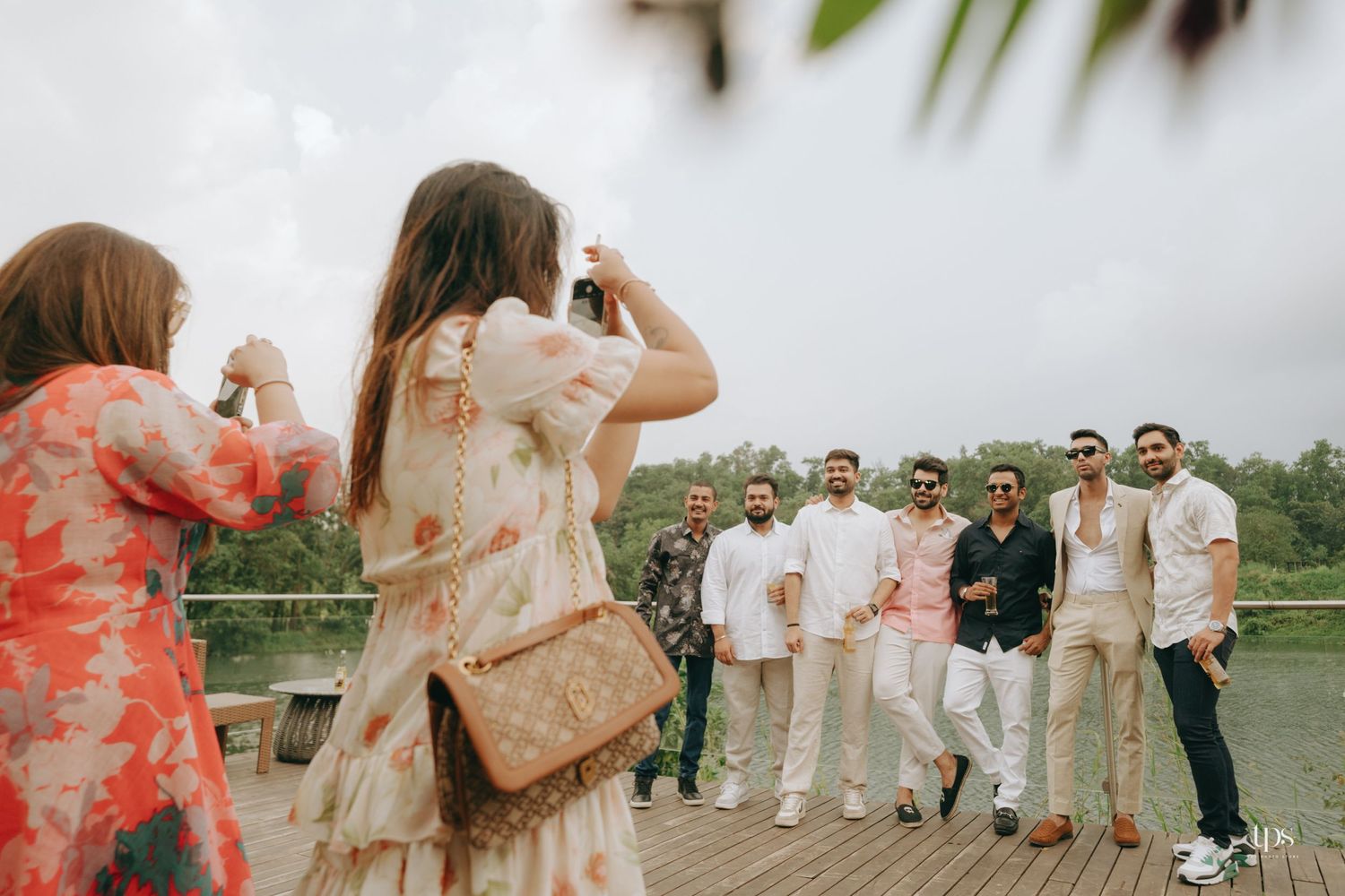 Wedding guests celebrate outdoors in coordinated coral and white outfits during a festive celebration.