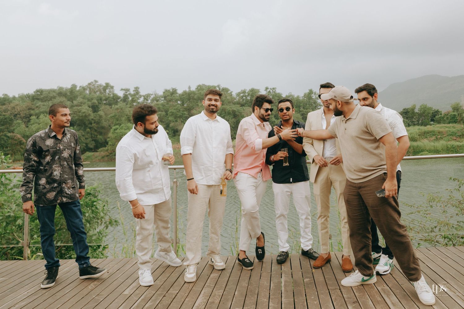 Wedding party poses on a wooden deck overlooking a scenic landscape.
