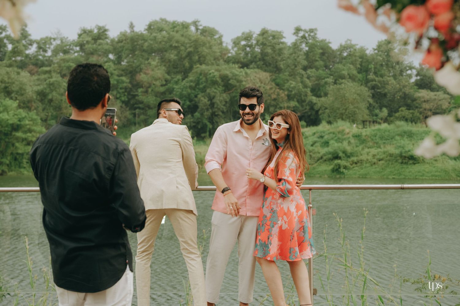 Outdoor wedding celebration with coral floral decorations and natural scenery in the background.