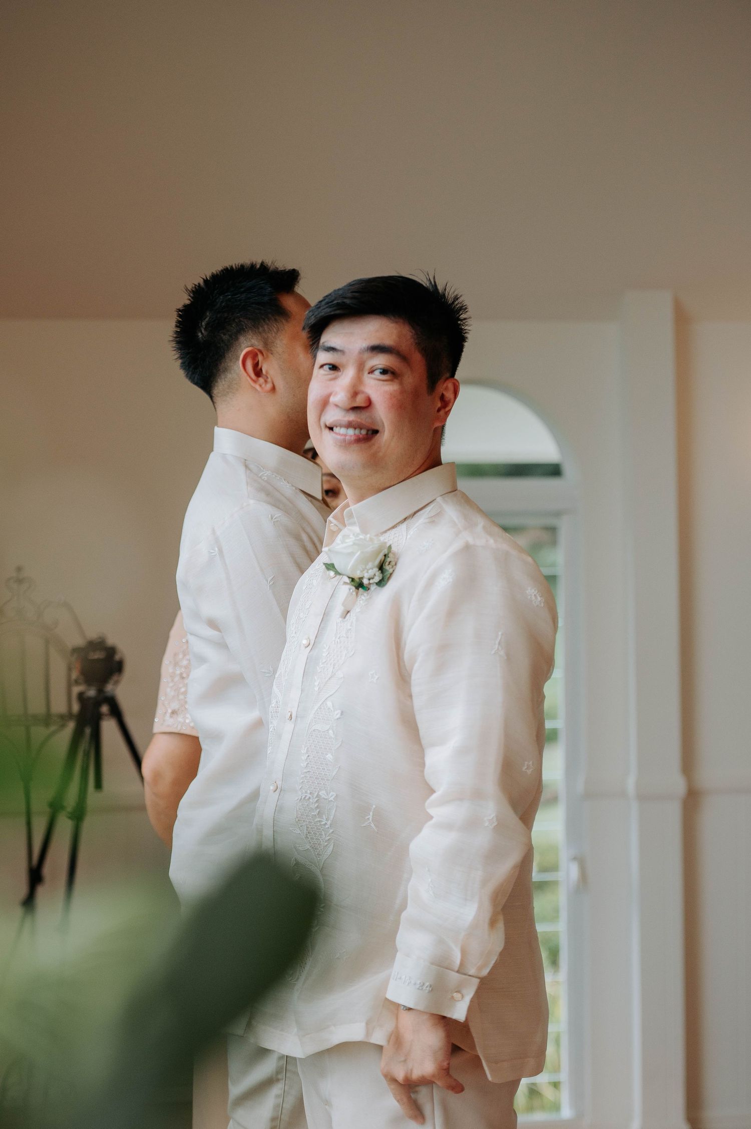Two people in white barongs share an intimate moment during a wedding photoshoot.