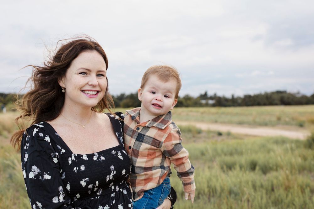 A joyful moment shared between a parent and child outdoors in a grassy field on a cloudy day.