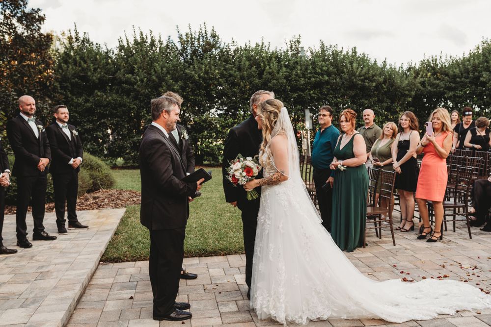 Wedding ceremony in progress with guests watching couple at altar.