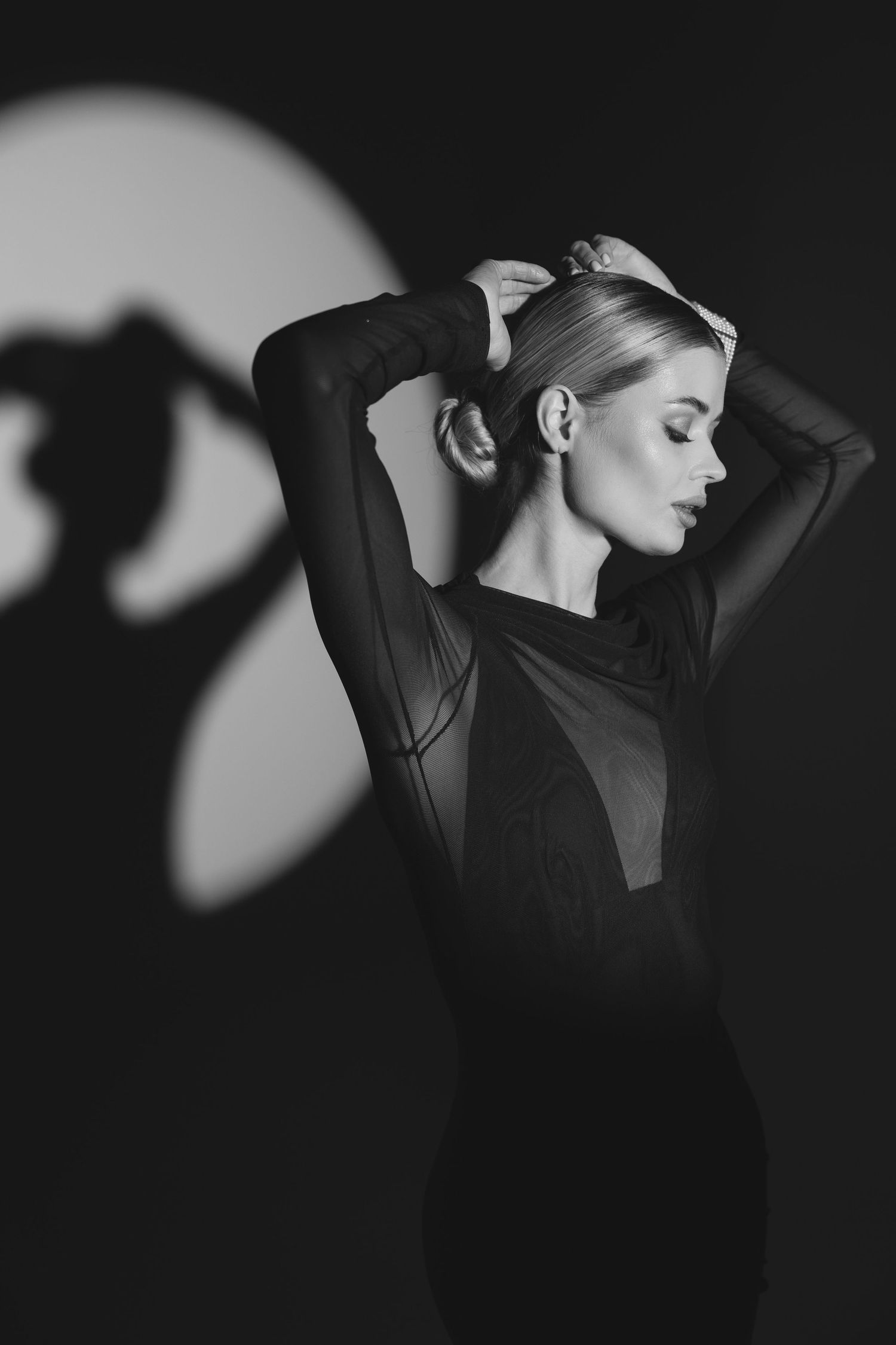 Artistic black and white portrait with dramatic shadow and flowing black garment.