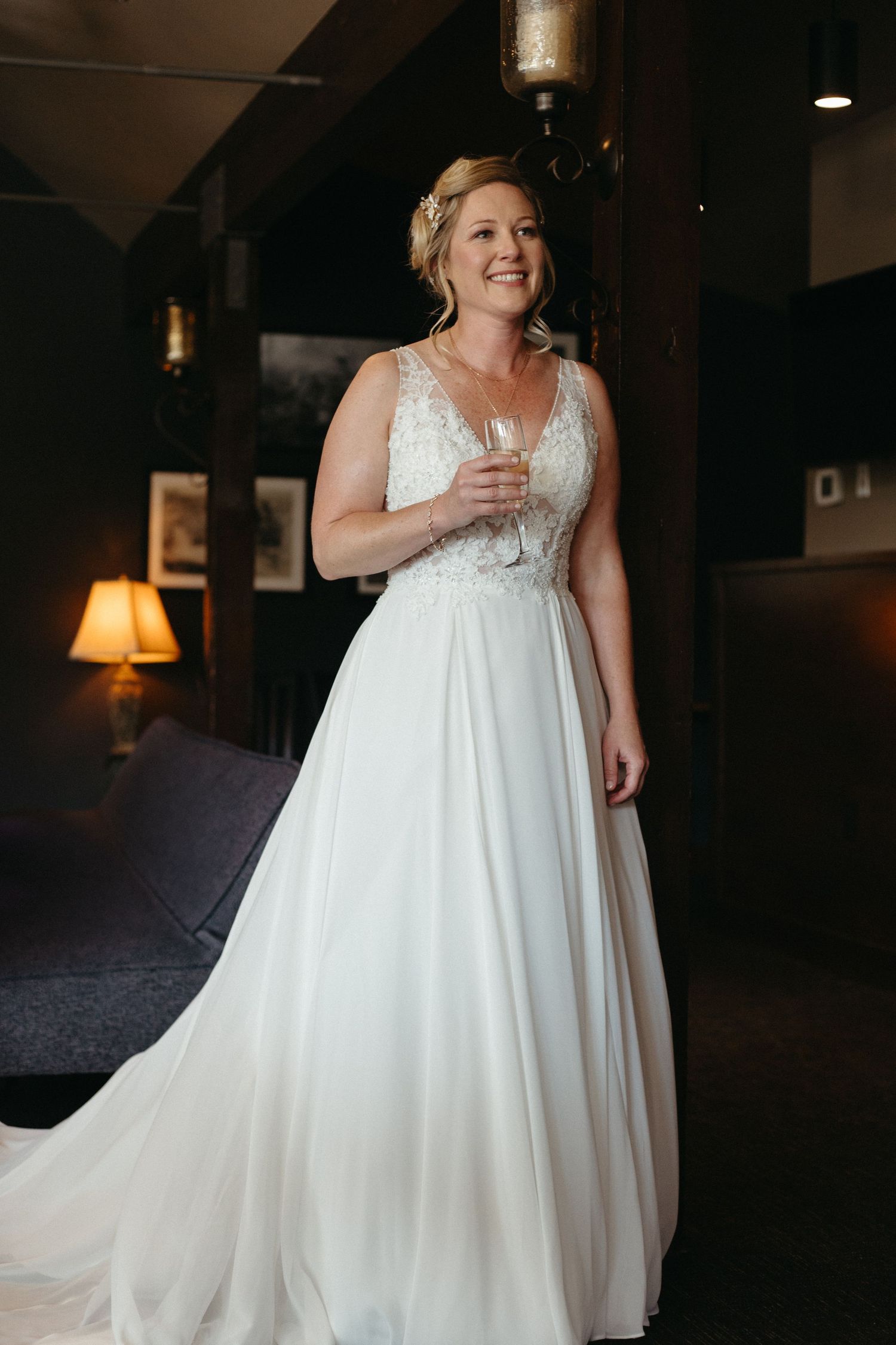 A flowing white wedding dress with lace bodice detail is showcased in a dimly lit room.