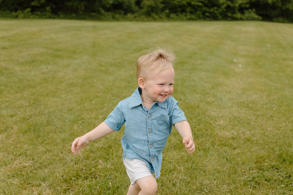 A person in denim clothing runs and plays on a lush green grass lawn on a sunny summer day.