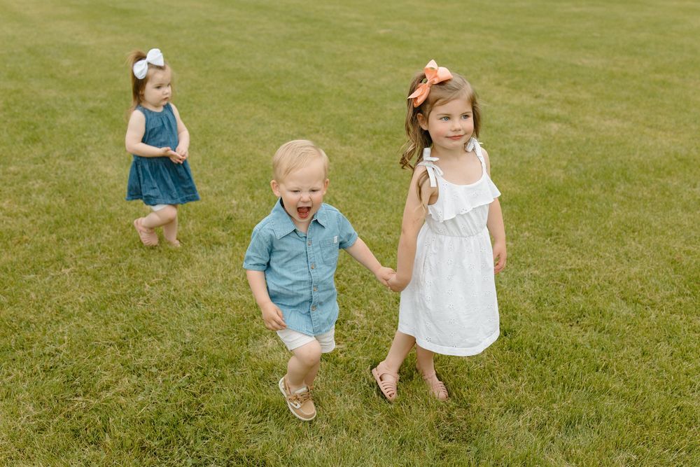 Carefree children running and playing together on a grassy lawn during a sunny summer day.