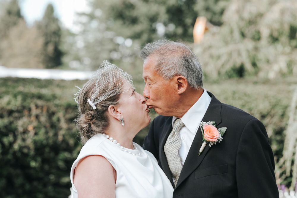 Intimate moment between couple in formal wedding attire outdoors.
