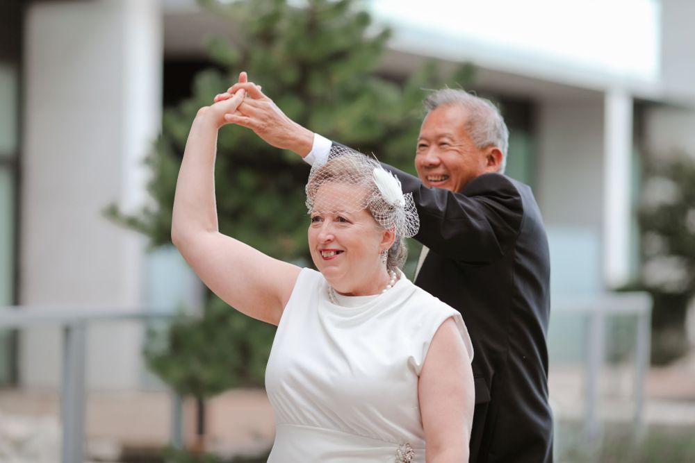 A couple dancing joyfully together at an outdoor wedding celebration.