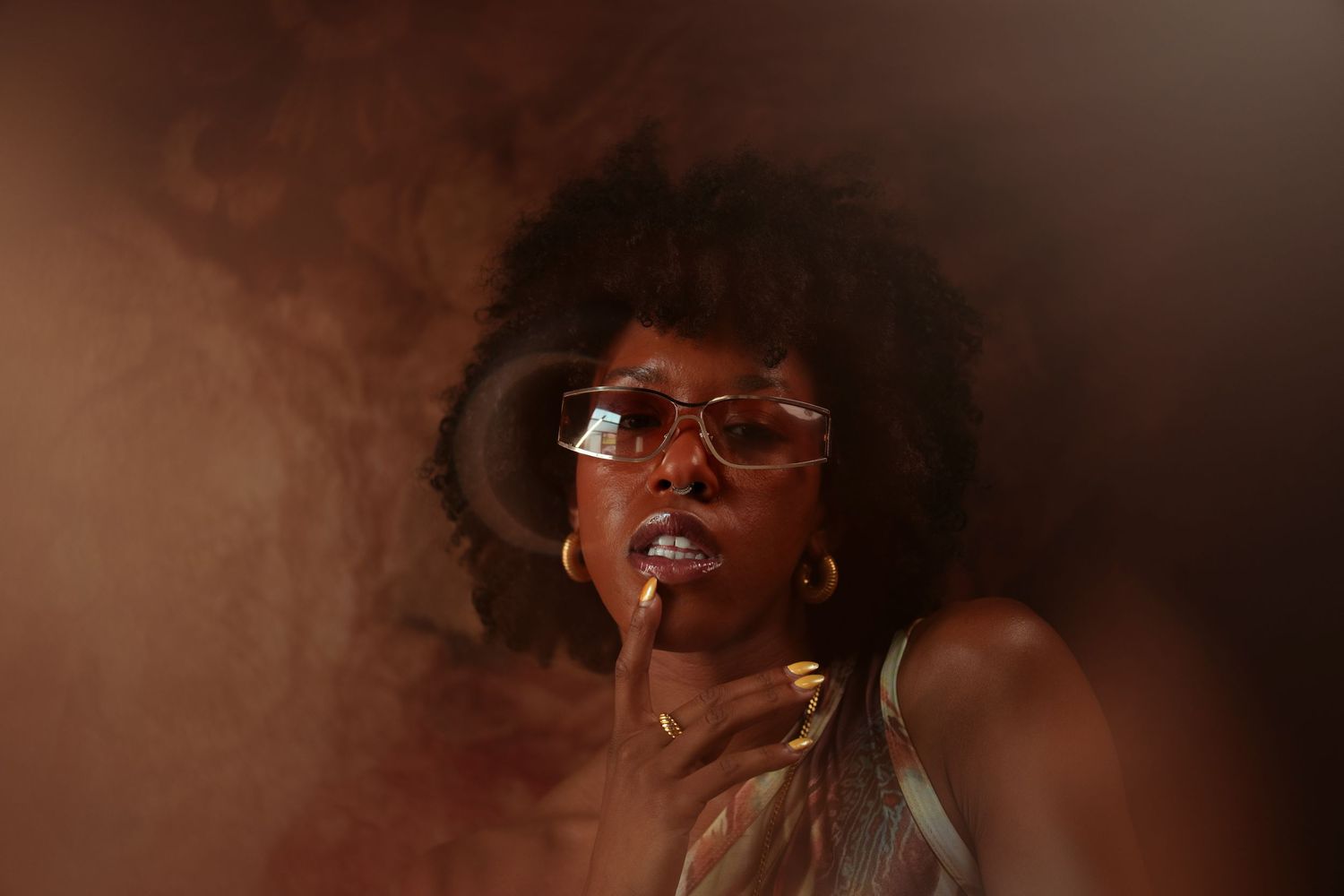 Moody portrait with glasses and smoke effects in sepia tones.