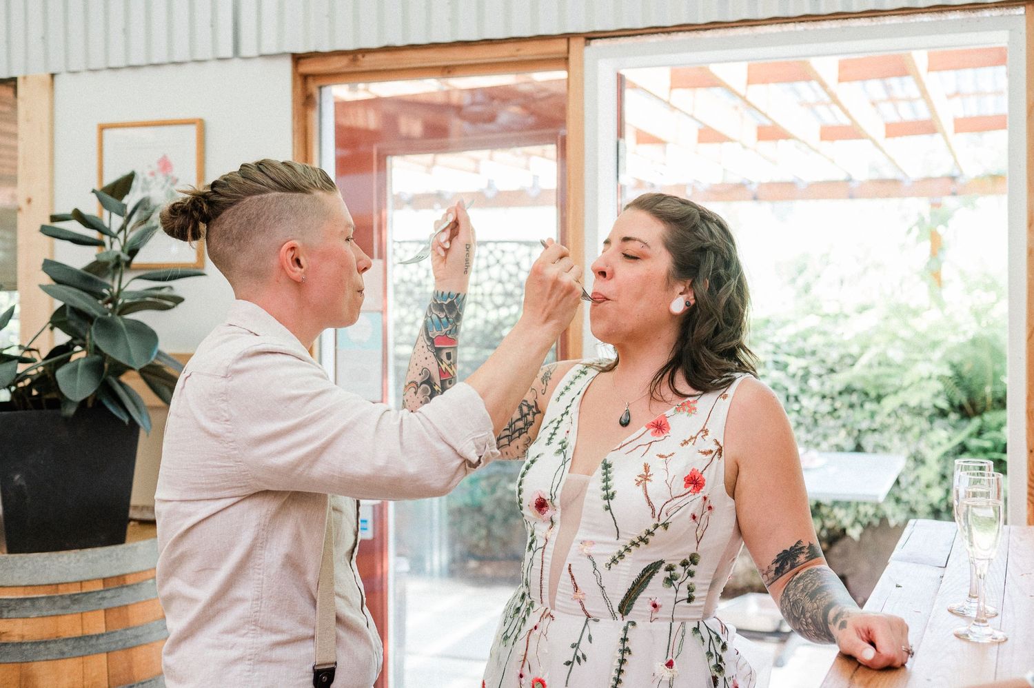 two brides sharing cake with one another during their wedding reception