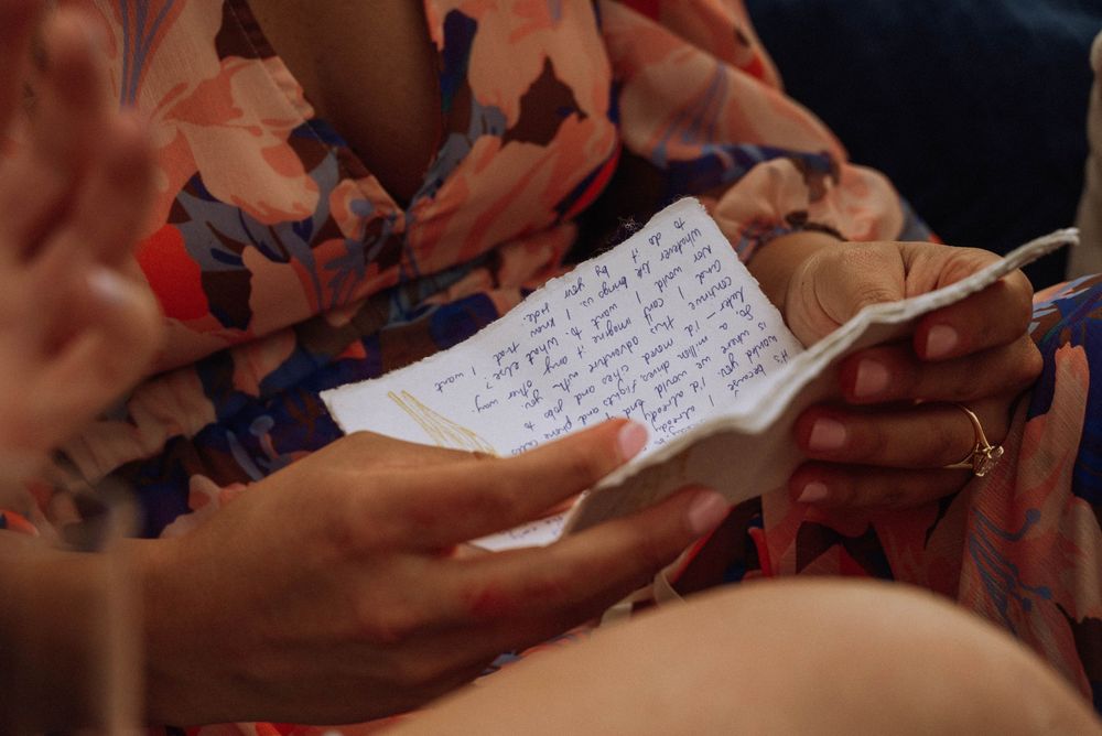 Close-up of hands holding a small notebook with handwritten wedding vows in soft light.