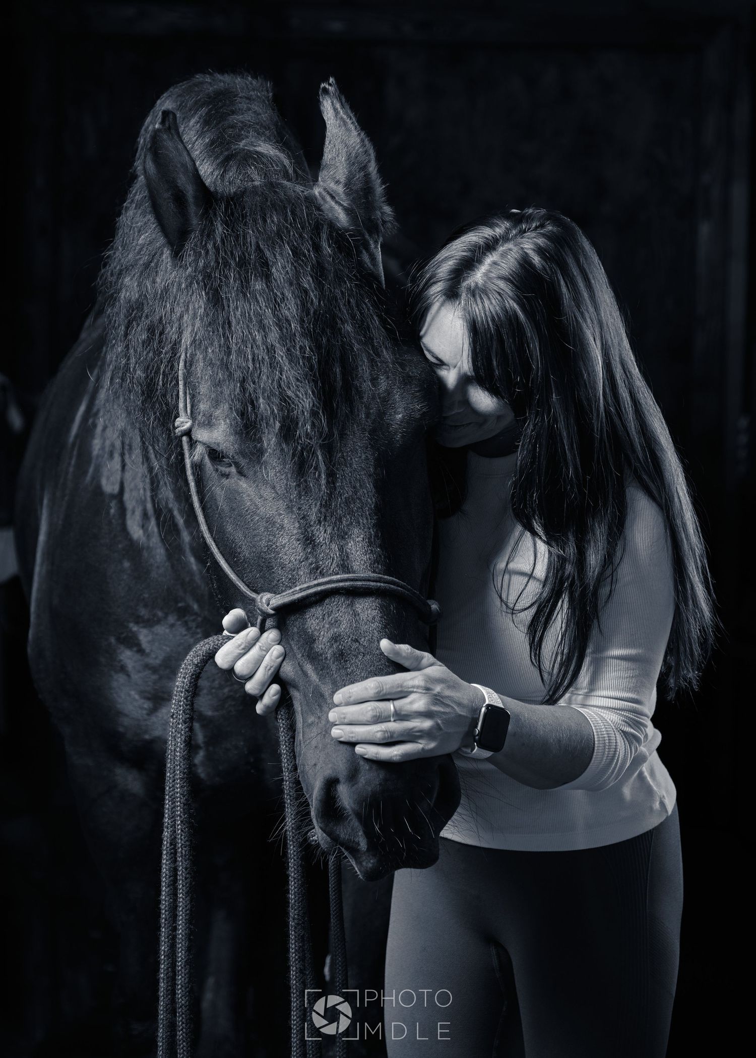 Une femme dépose sa tête contre le museau de son cheval dans un geste délicat.