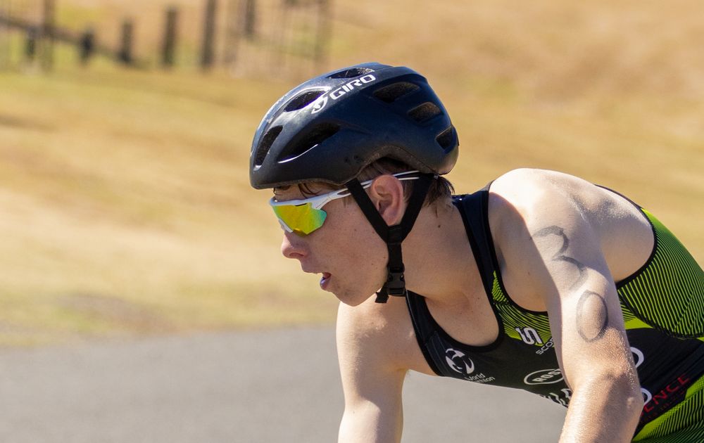 Close-up of a cyclist in aerodynamic position wearing a Giro helmet and yellow-framed sunglasses.