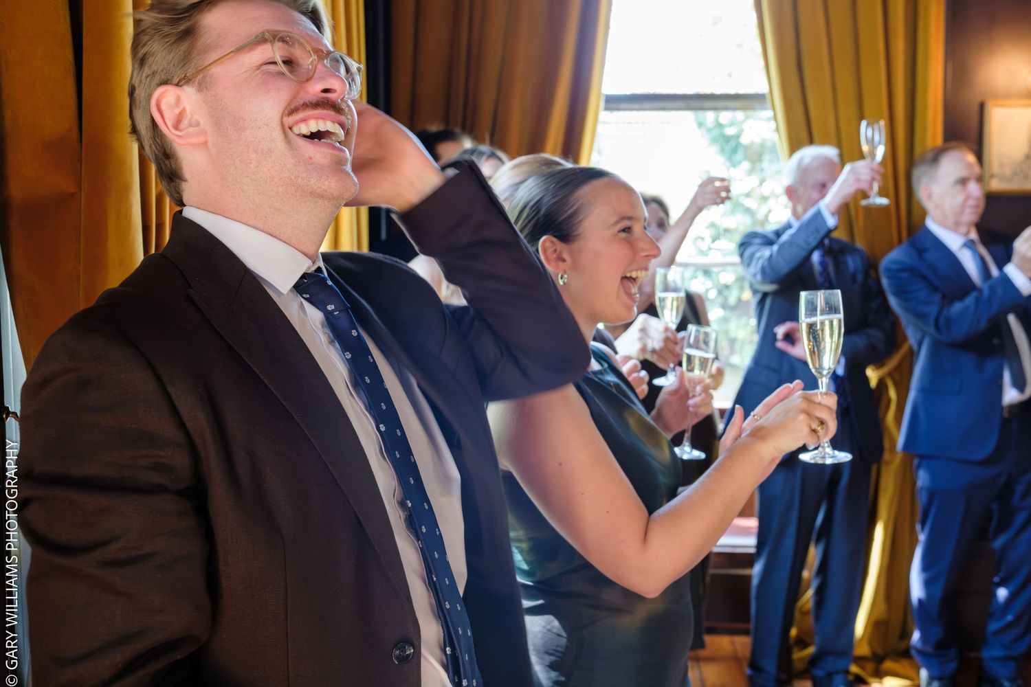Guests laughing and toasting with champagne glasses at an elegant wedding reception at the Canonbury Tavern in Islington