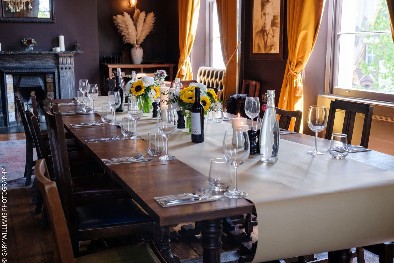 Elegant dining room with long wooden table set with wine glasses, sunflowers, and candles at the Canonbury Tavern