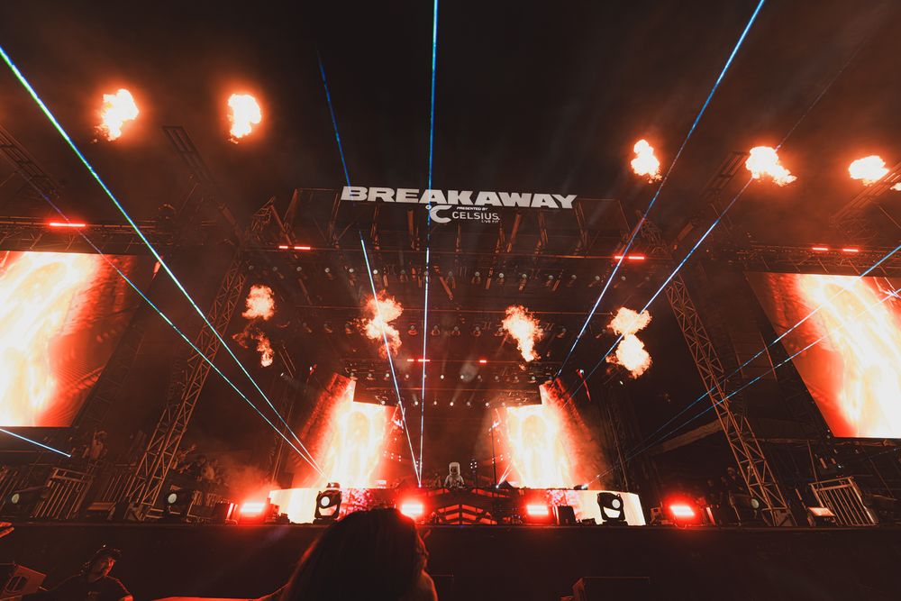 Breakaway Music Festival stage with dramatic fire effects and laser lights illuminating the night sky.