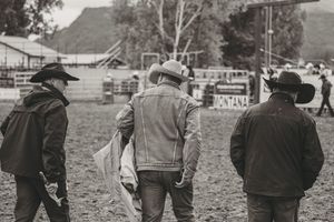 Black and white photo of three cowboys walking across a rodeo arena in Montana.