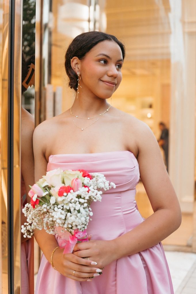 Elegant woman in strapless pink satin dress holding colorful bridal bouquet with roses and baby's breath.