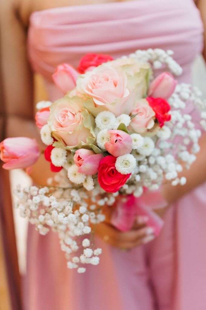 Close-up of bridal bouquet featuring pink tulips, red roses, white flowers, and delicate baby's breath.