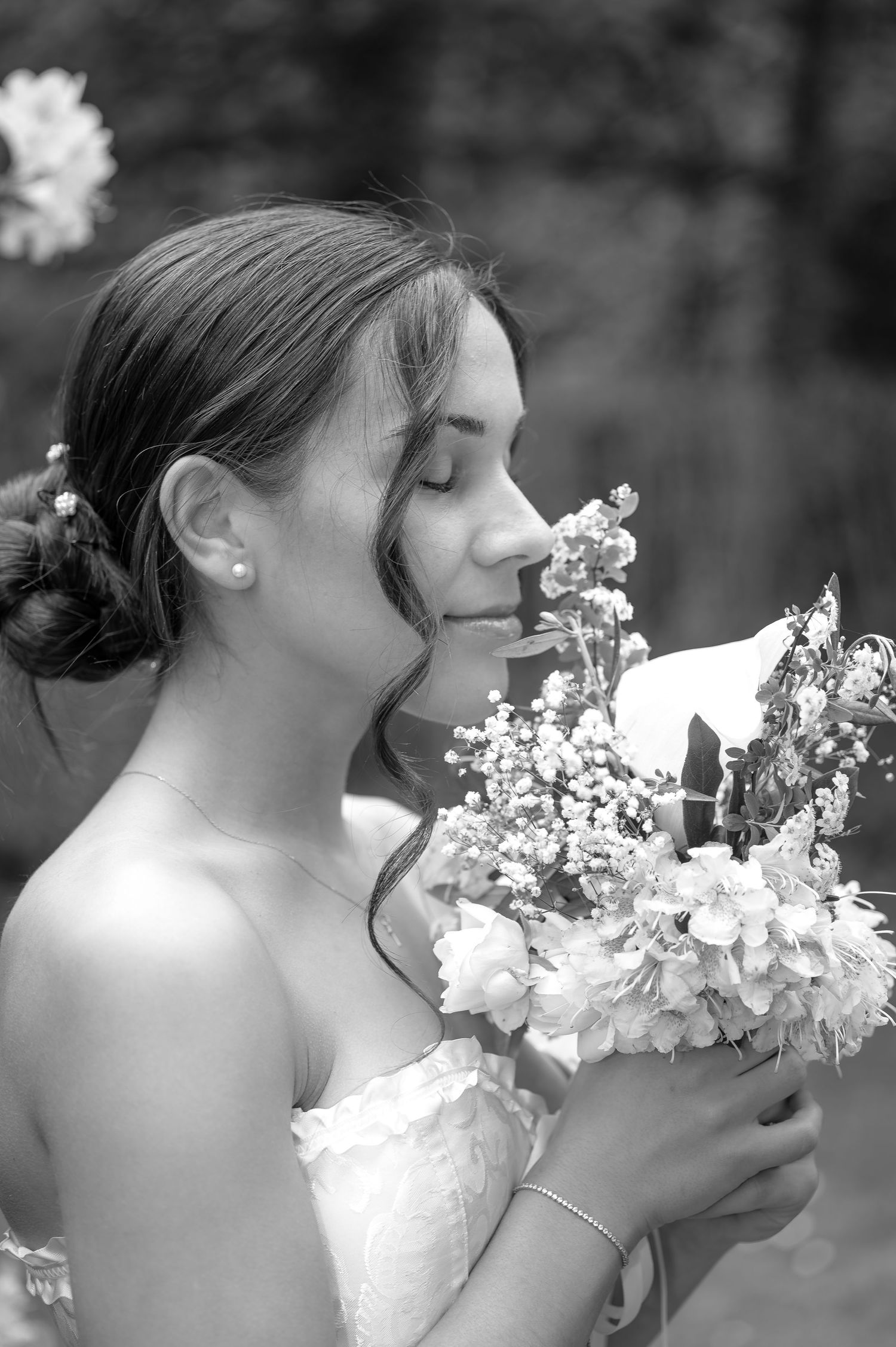 Black and white portrait of a bride smelling her wedding bouquet of flowers with eyes closed.