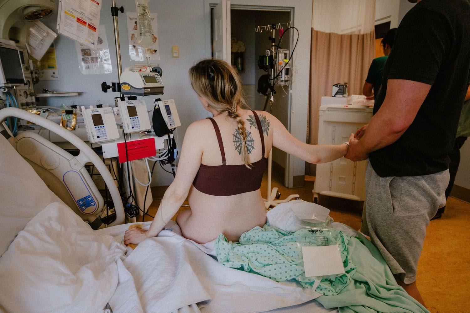 Medical professionals work intently in a dimly lit hospital room with medical equipment visible in the background.