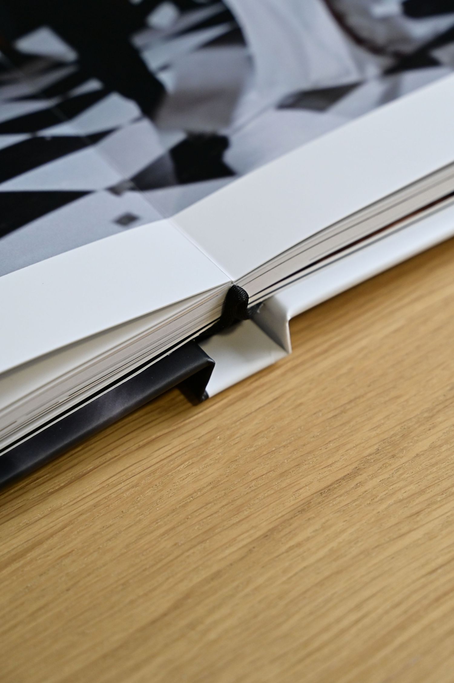 Close-up of open hardcover book binding showing black ribbon bookmark and thick pages.