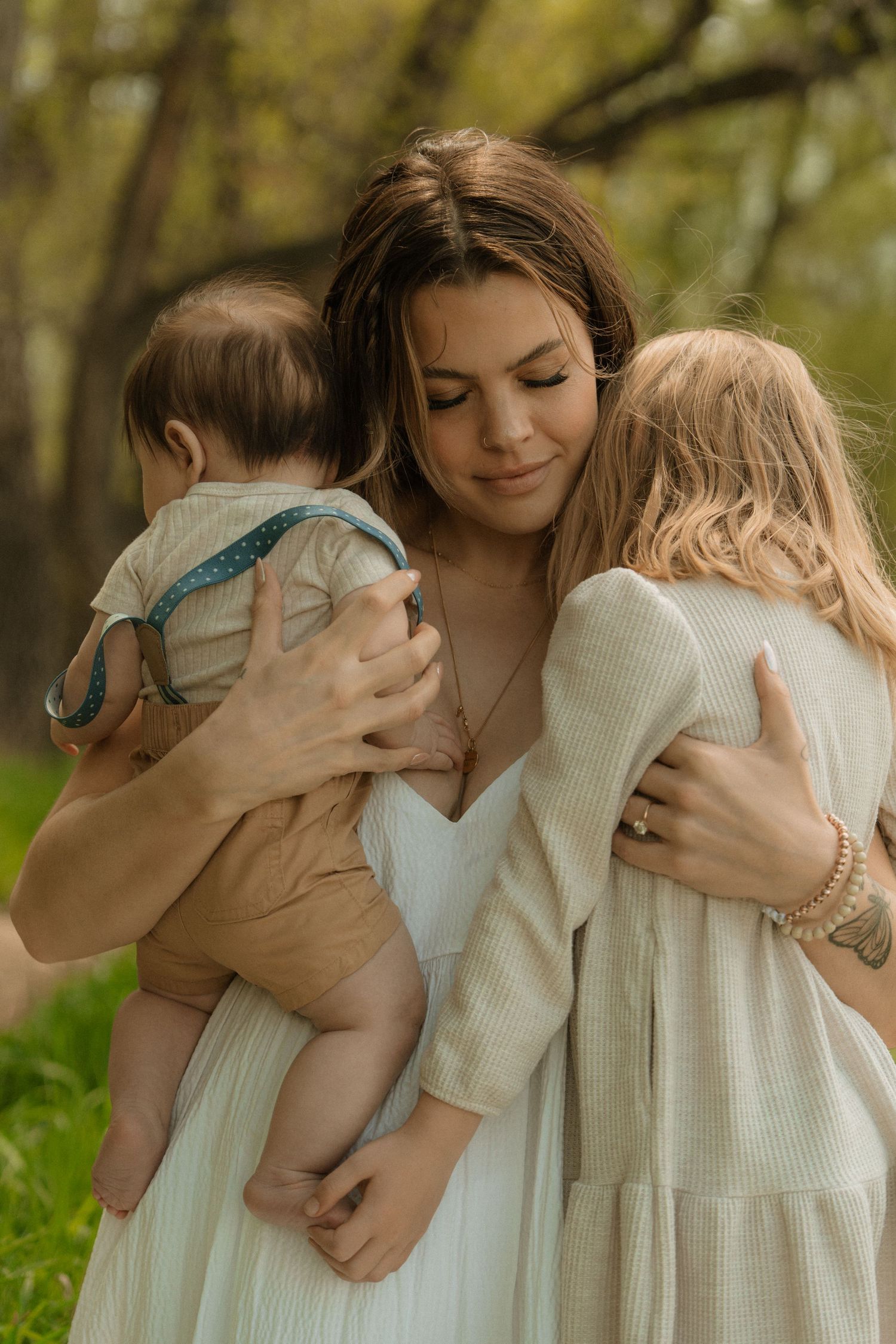A young boy in a blue shirt covers his face with his hands while sitting between his parents during a family photo session.