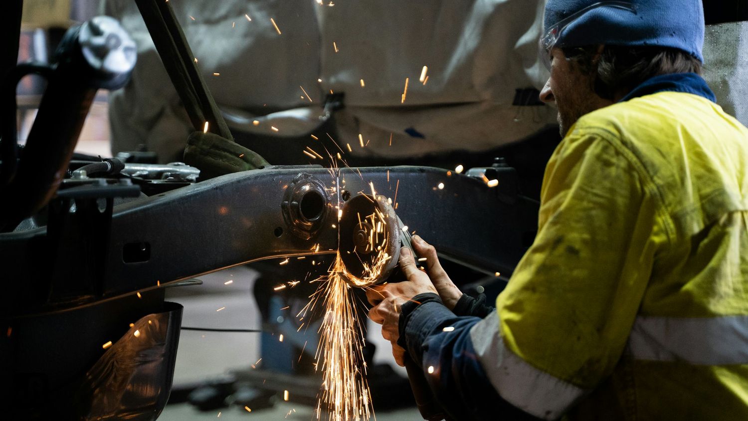 Man modifying a vehicle with an angle grinder
