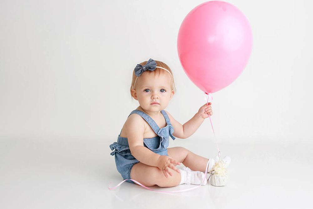 Winchester CA baby photographer photo of one year old baby girl holding a pink balloon for 1st birthday photos.