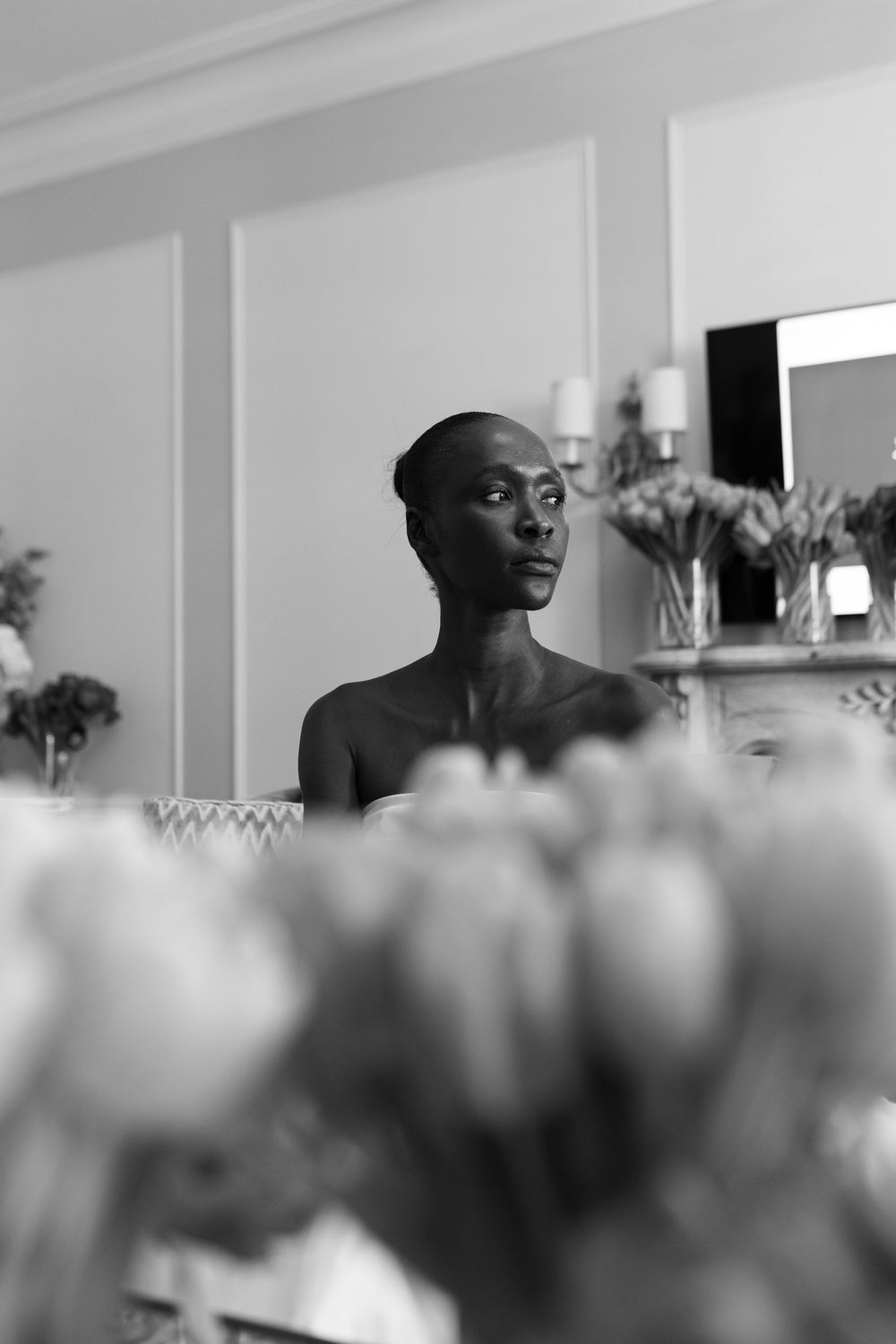 Elegant black and white portrait of a woman surrounded by tulips in a luxurious room.